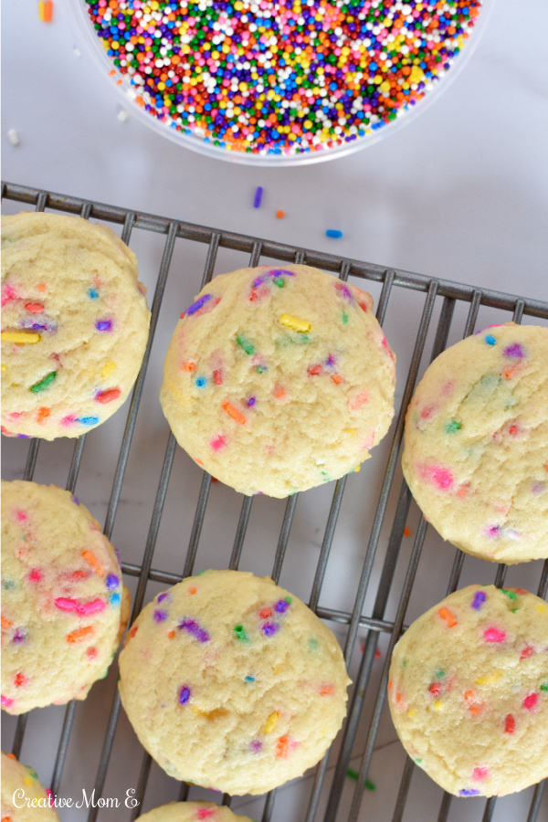 Sprinkle sugar cookies on a cooling rack with a bowl of sprinkles next to them