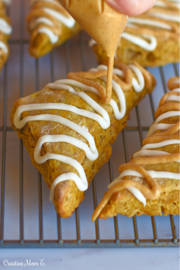 Classic Pumpkin spice scones on a cooling rack being drizzled with a powdered sugar icing.