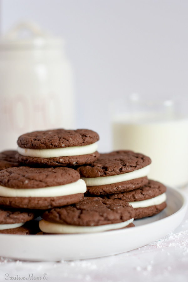 Chocolate Crinkle Cookies on a white plate with a glass of milk and cookie jar in the background.