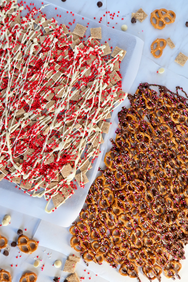 A baking sheet covered with white chocolate Chex mix and pretzels with chocolate drizzle covered with sprinkles. 
