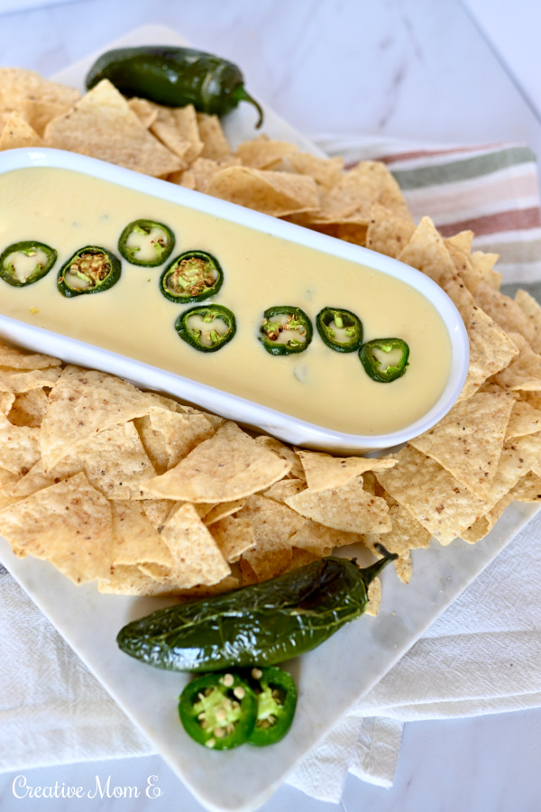 White Jalapeño cheese dip in a white dish surrounded by chips.