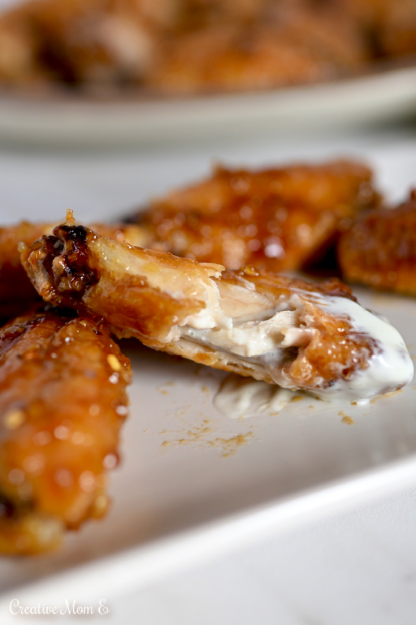 Crispy Chicken wing with a bite taken out of it sitting on a white plate. 