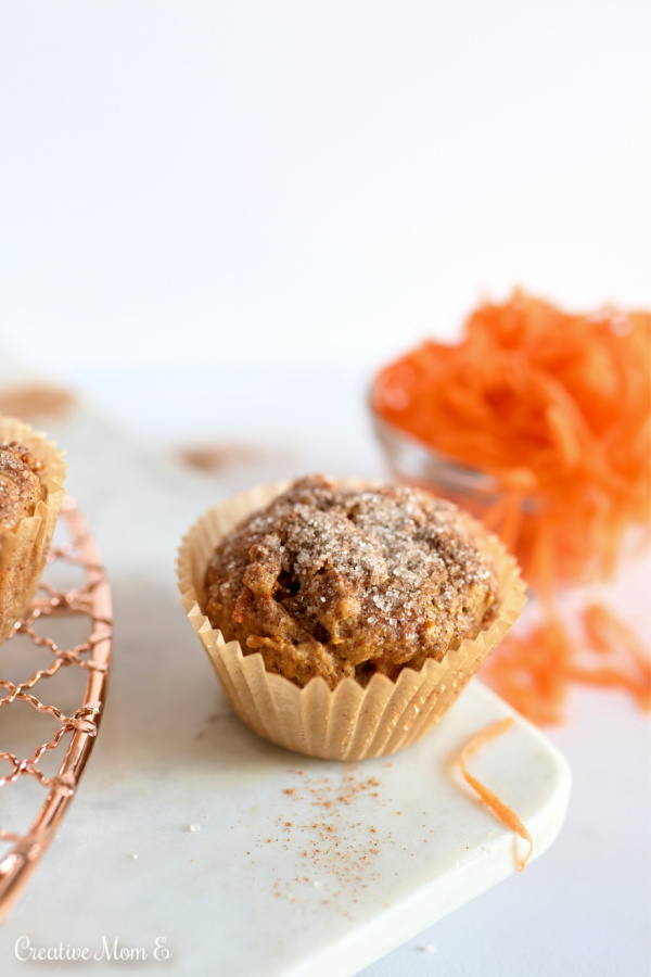 Carrot Cake muffin with a side of carrots on a white marble slab. 