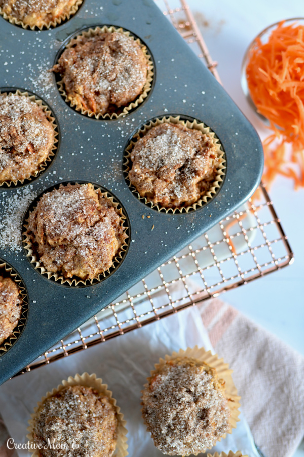 A muffin pan filled with muffins with a side of carrots. 