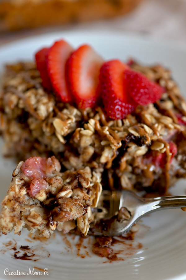 A fork full of chocolate strawberry baked oatmeal with almond butter drizzled on it. 