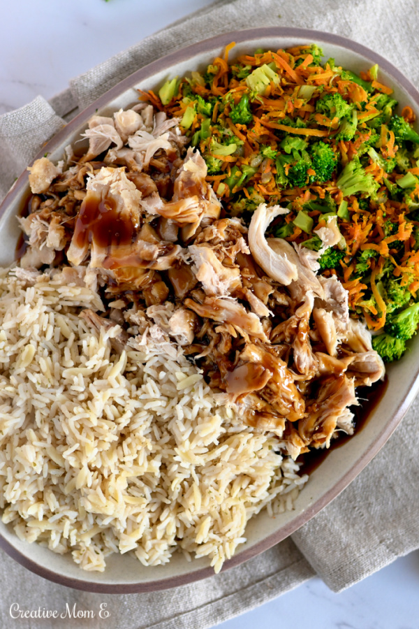 A tan platter with rice, chicken teriyaki, broccoli and shredded rice. 