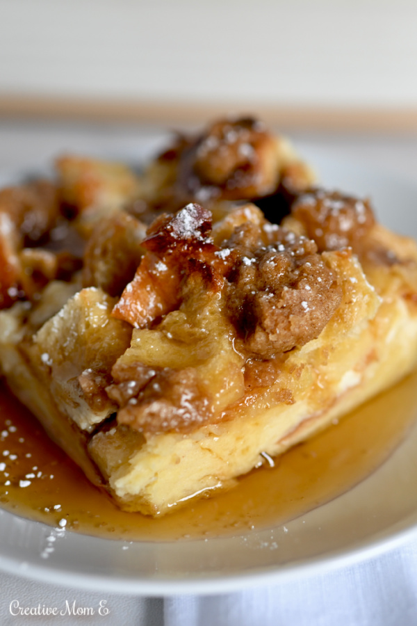 French Toast covered in syrup and powdered sugar on a white plate. 