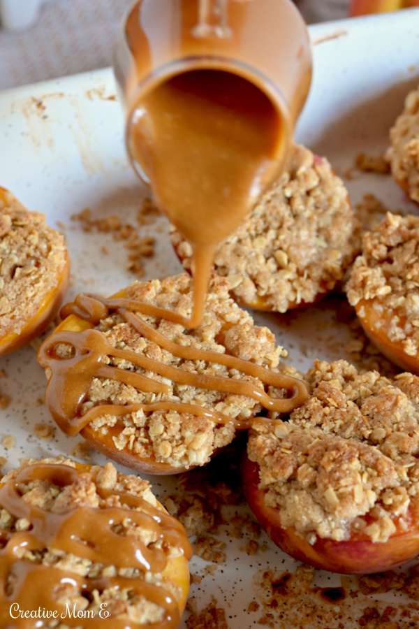 Pan filled with an oat crumble topping on peaches being drizzled by caramel. 