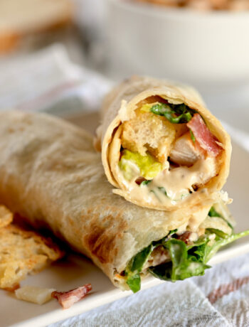 Chicken Caesar Salad Wrap on a white plate with a side of bbq chips.