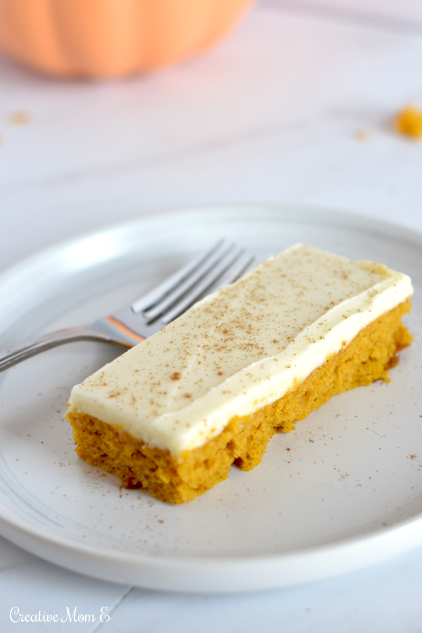 Baked pumpkin bar slice on a white plate with a fork. 