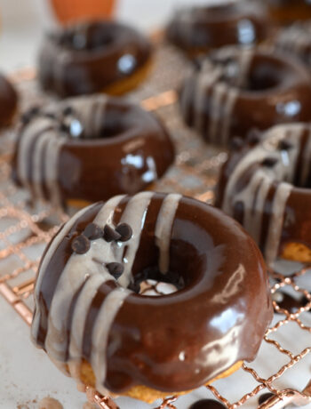 Pumpkin Cake Donuts with a chocolate glaze on a copper cooling rack.